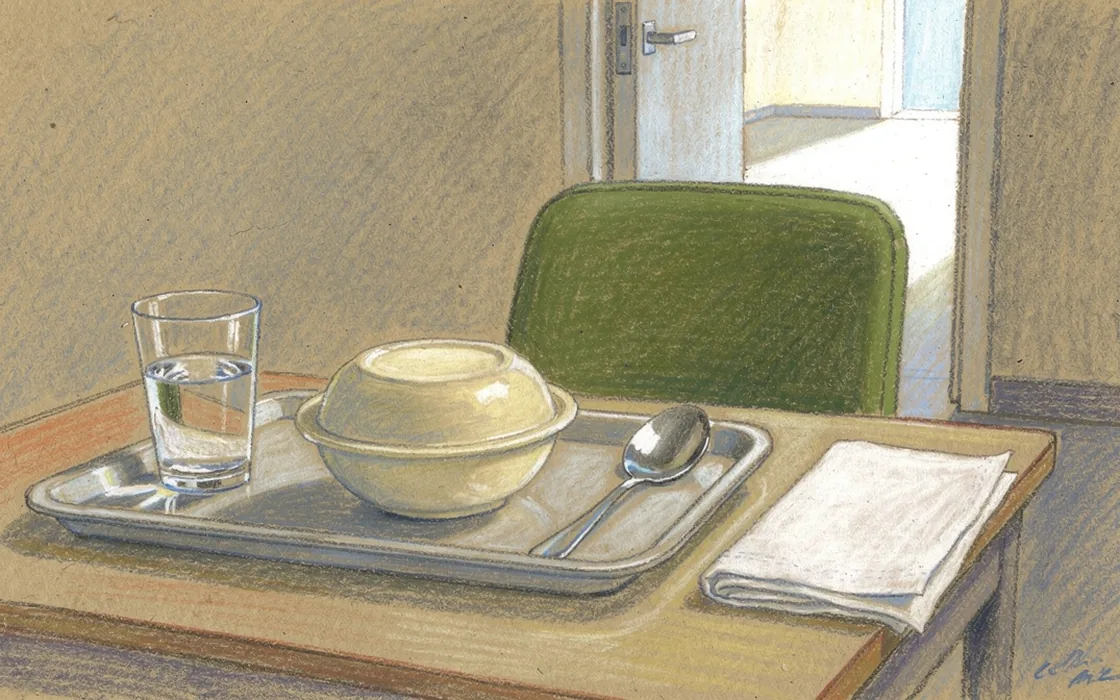 A covered meal tray beside an empty hospital recovery-room chair